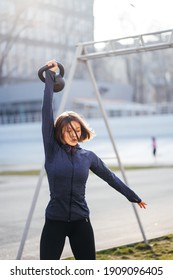 Young Woman Exercising With A Kettlebell Outside At Stadium