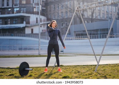 Young Woman Exercising With A Kettlebell Outside At Stadium