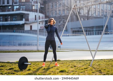 Young Woman Exercising With A Kettlebell Outside At Stadium