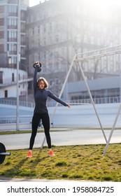 Young Woman Exercising With A Kettlebell Outside At Stadium