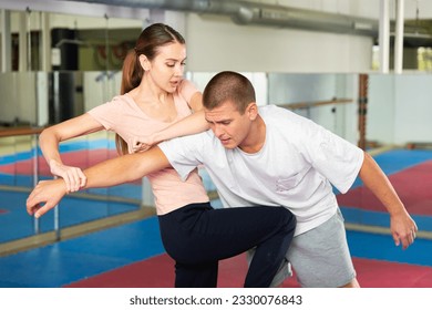 Young woman exercising knee strike on man during self-protection training. - Powered by Shutterstock