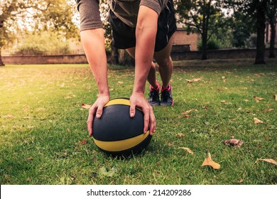 A young woman is exercising with a medicine ball in the park on a cloudy day - Powered by Shutterstock