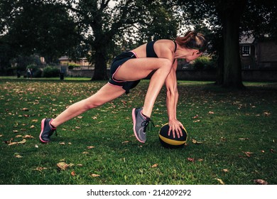 A young woman is exercising with a medicine ball in the park on a cloudy day - Powered by Shutterstock