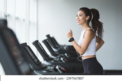 Young woman exercising on treadmill and listening music in the gym, copy space - Powered by Shutterstock