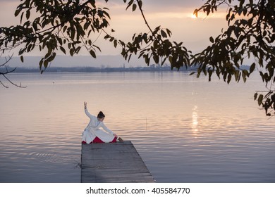 a young woman exercising shadowbox beside the lake in the morning.
