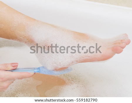 Young woman exfoliating her foot with a pumice stone. Pumice foot file.