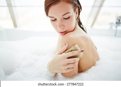 Young Woman Exfoliating Her Skin With Soap In Bath