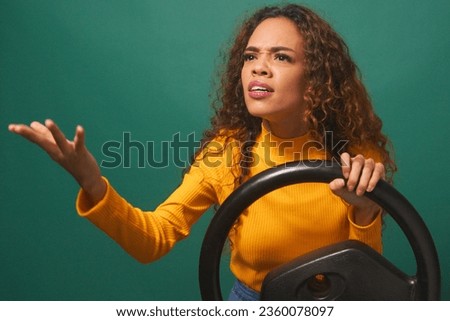 Young woman experiences road rage, angry while driving, green studio background
