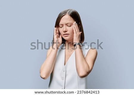 Young woman experiencing stress headache, on gray background
