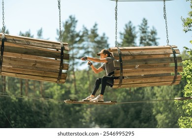 A young woman expertly navigates through a thrilling high ropes course, surrounded by lush trees and warm sunlight - Powered by Shutterstock