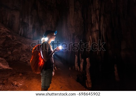 Young woman explores the cave with a torch