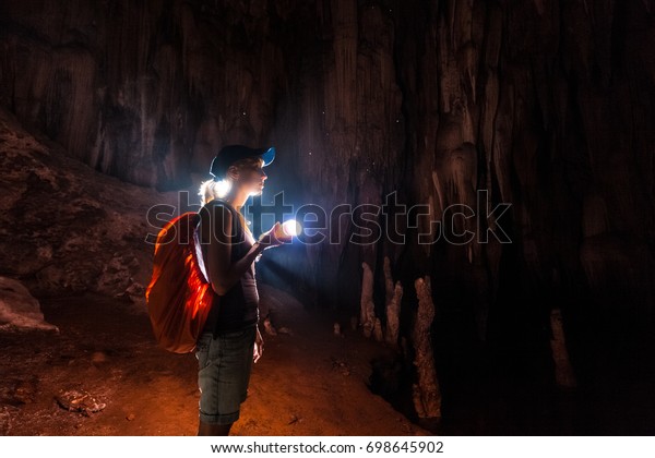 Young woman explores\
the cave with a torch