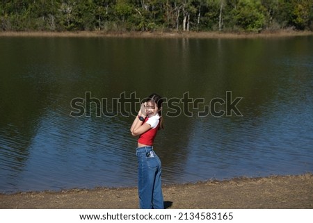 A young woman is exploring nature in a green forest with trees and rivers during the day on vacation.