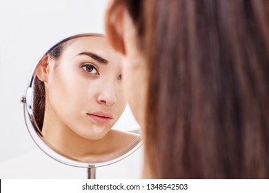 Young Woman With Eyes Bruises Looks On Her Reflection In The Mirror.