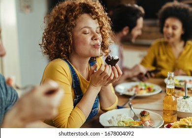 Young woman with eyes closed enjoying in taste of food while eating with friends at dining table.  - Shutterstock ID 1678004092