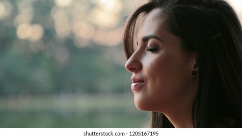 Young Woman With Eyes Closed Taking A Deep Breath Outside At The Park