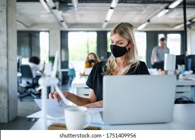 Young Woman With Face Mask Back At Work In Office After Lockdown, Working.