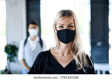 Young woman with face mask back at work in office after lockdown, looking at camera. - Powered by Shutterstock
