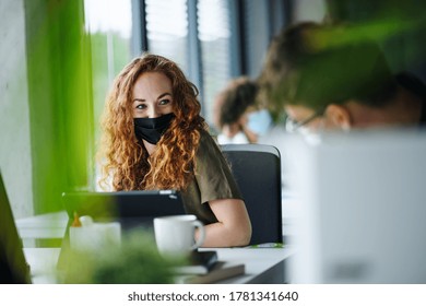 Young woman with face mask back at work in office after lockdown. - Powered by Shutterstock