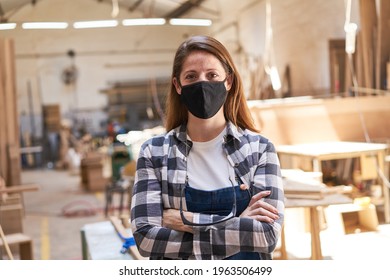 Young Woman With Face Mask Because Of Covid-19 As A Carpenter Apprentice In The Workshop