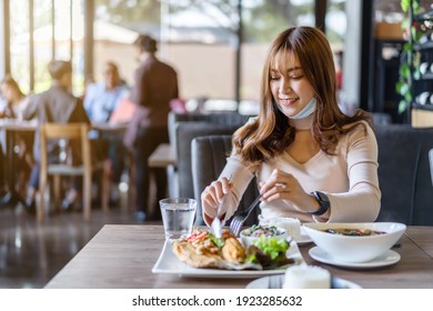 Young Woman With Face Mask Eating A Food In Restaurant, New Normal Concept For Protect Coronavirus (Covid-19) Pandemic