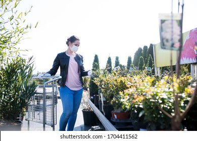 Young Woman With Face Mask Outdoors Shopping In Garden Center, Corona Virus Concept.