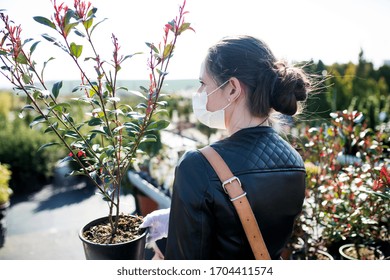 Young Woman With Face Mask Outdoors Shopping In Garden Center, Corona Virus Concept.