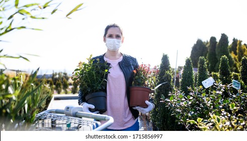 Young Woman With Face Mask Outdoors Shopping In Garden Center, Corona Virus Concept.