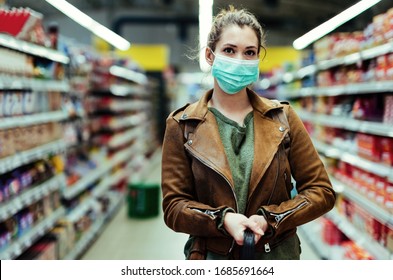 Young woman with face mask standing at supermarket aisle while buying during virus pandemic.  - Powered by Shutterstock