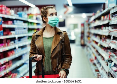 Young Woman With Face Mask Walking Through Grocery Store During COVID-19 Pandemic. 