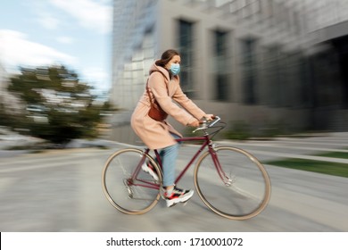 Young woman in face medical mask riding bicycle roadway motion blur - Powered by Shutterstock