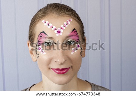 Young woman with face painting pink butterfly mask
