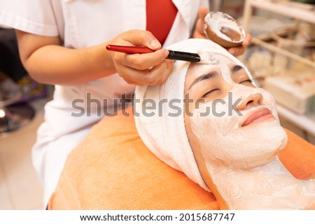 young woman with facial mask at beauty spa salon