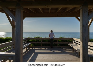 Young woman facing the ocean from the lookout of the beach in Inverness, Cape Breton Island - Nova Scotia
