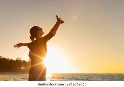 Young woman facing ocean sunset  rejoices, laughs, smiles looking up to the sky, enjoys life and summer, nature, happiness.	 - Shutterstock ID 2262062865
