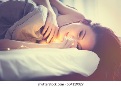 Young Woman With Fairy Lights Dreaming In Bed