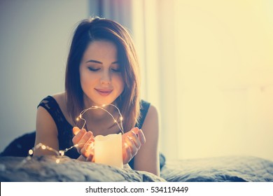 Young Woman With Fairy Lights Dreaming In Bed