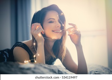 Young Woman With Fairy Lights Dreaming In Bed 