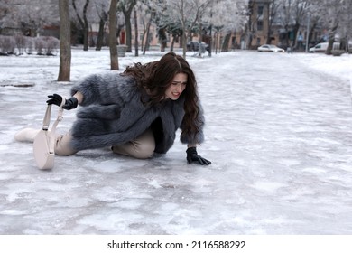 Young Woman Fallen On Slippery Icy Pavement In Park