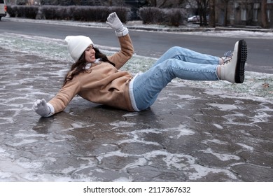 Young woman fallen on slippery icy pavement outdoors