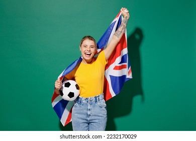 Young woman fan wear basic yellow t-shirt cheer up support football sport team hold in hand UK British flag soccer ball watch tv live stream do winner gesture isolated on dark green background studio - Powered by Shutterstock