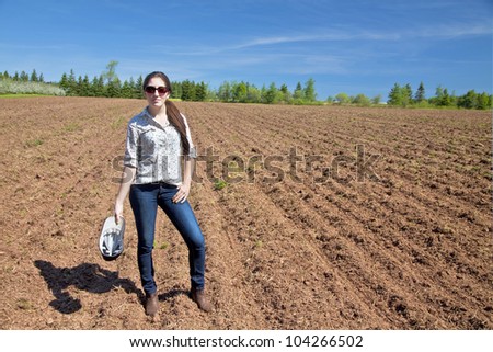Young woman farmer standing in front of a newly seeded field.