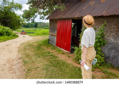 Young Woman Farmer Or Teenager Looking At Tractor On A Local Farm In Canada  With A Basket In Light Cloths And Strain  Hat