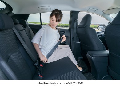 young woman fastening a seat belt of motor vehicle