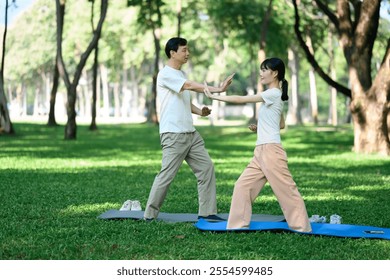 Young woman and father performing Tai Chi exercises together in a park. Healthy and outdoor activity concept - Powered by Shutterstock