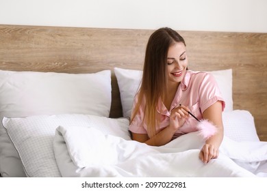 Young Woman With Feather Stick In Bedroom