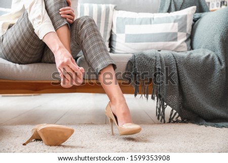 Young woman feeling ache because of wearing high heels at home