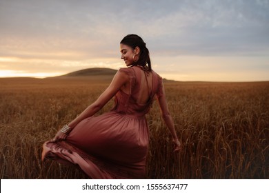 Young woman feeling happy in field of wheat crop at sunset. Female enjoying a day in nature. - Powered by Shutterstock