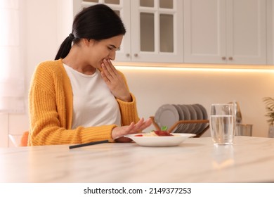 Young Woman Feeling Nausea While Seeing Food At Table In Kitchen