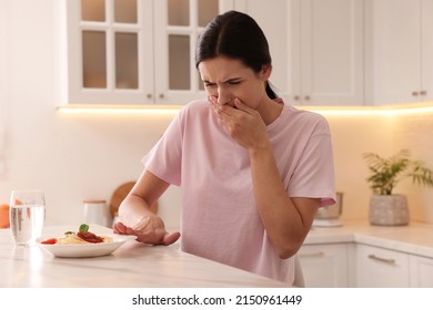 Young Woman Feeling Nausea While Seeing Food At Table In Kitchen